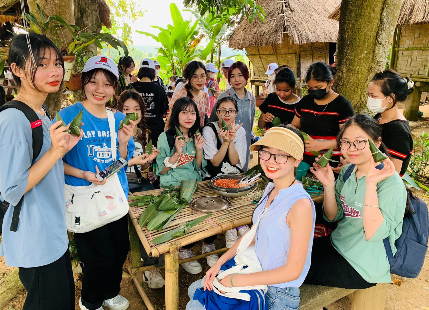 Du khách và thiếu nhi tham gia trải nghiệm làm bánh tình yêu dân tộc Tà Ôi tại Làng Văn hóa - Du lịch các dân tộc Việt Nam